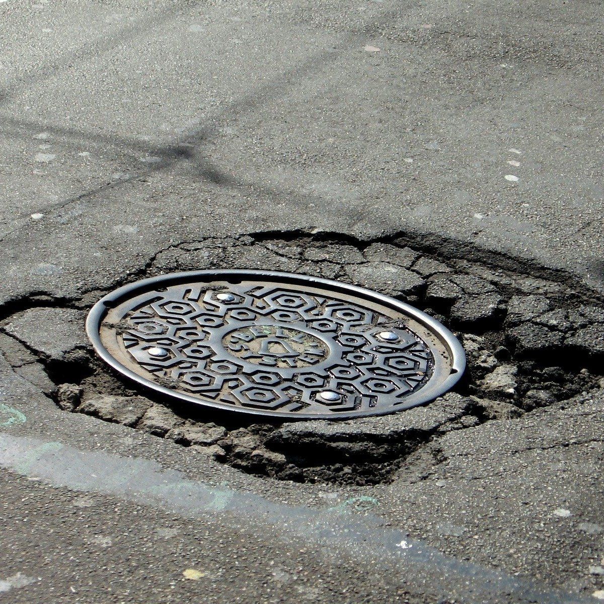 Damaged manhole cover set in cracked asphalt on a street