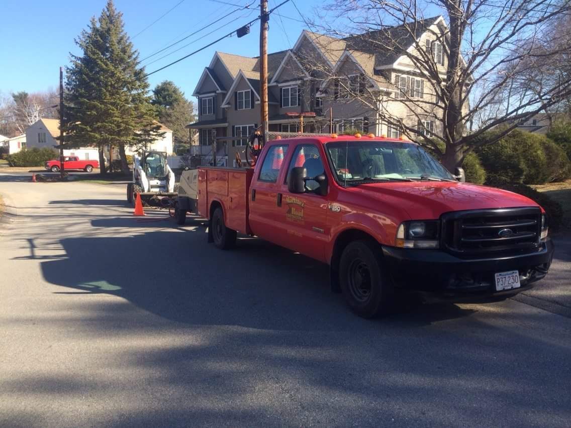 Red pickup truck towing a trailer on a residential street on a sunny day