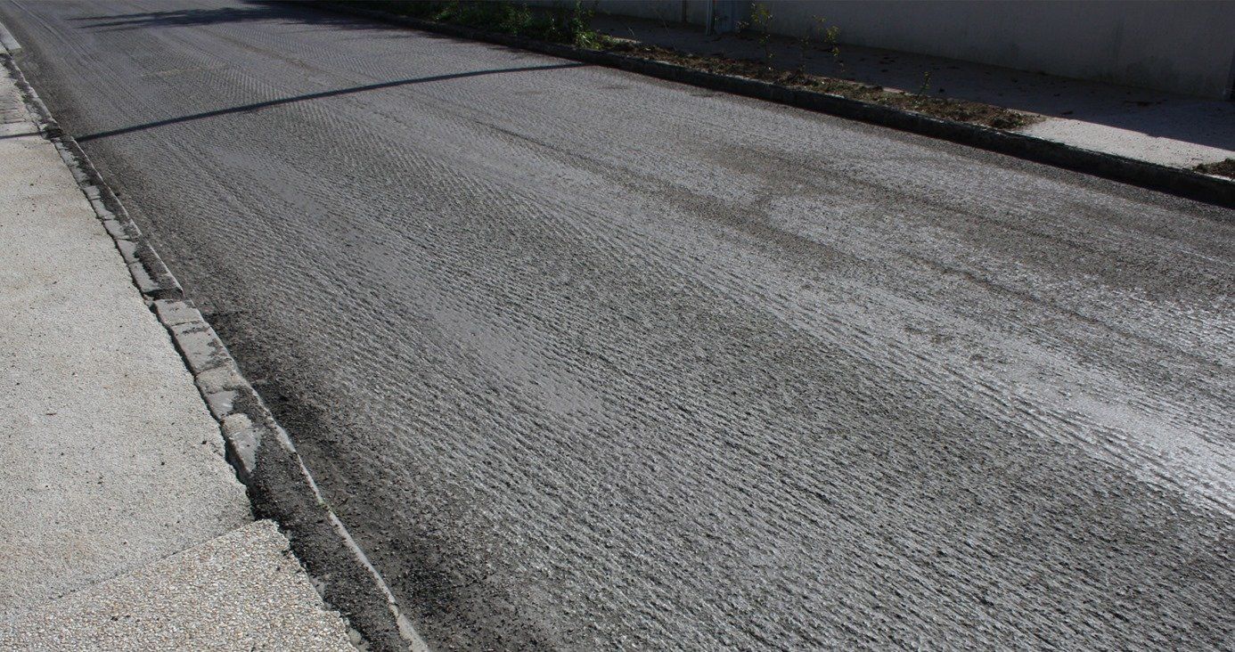 Empty paved road with a curb and sidewalk along the left side.