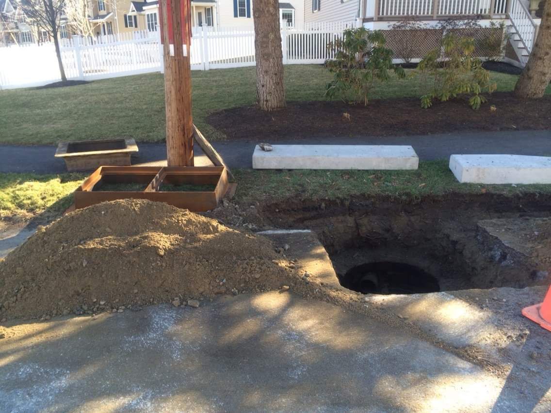 Backyard excavation with a large hole, dirt pile, and a support brace around a tree stump