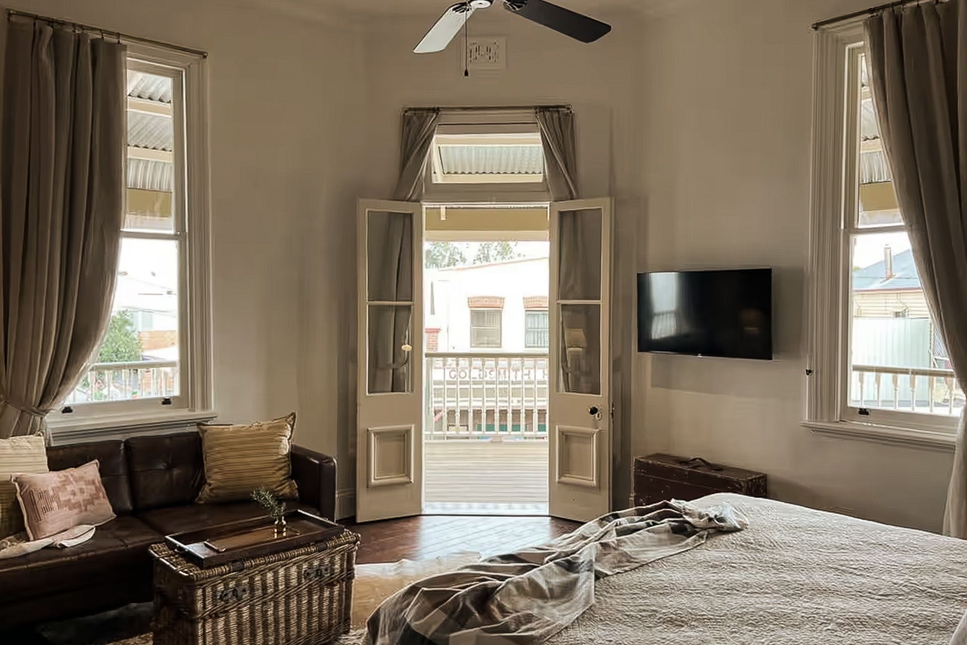A bedroom with a bed , couch , television and a balcony.