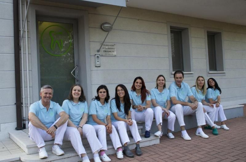 Persone in camici azzurri sedute su una veranda all'esterno di un edificio bianco