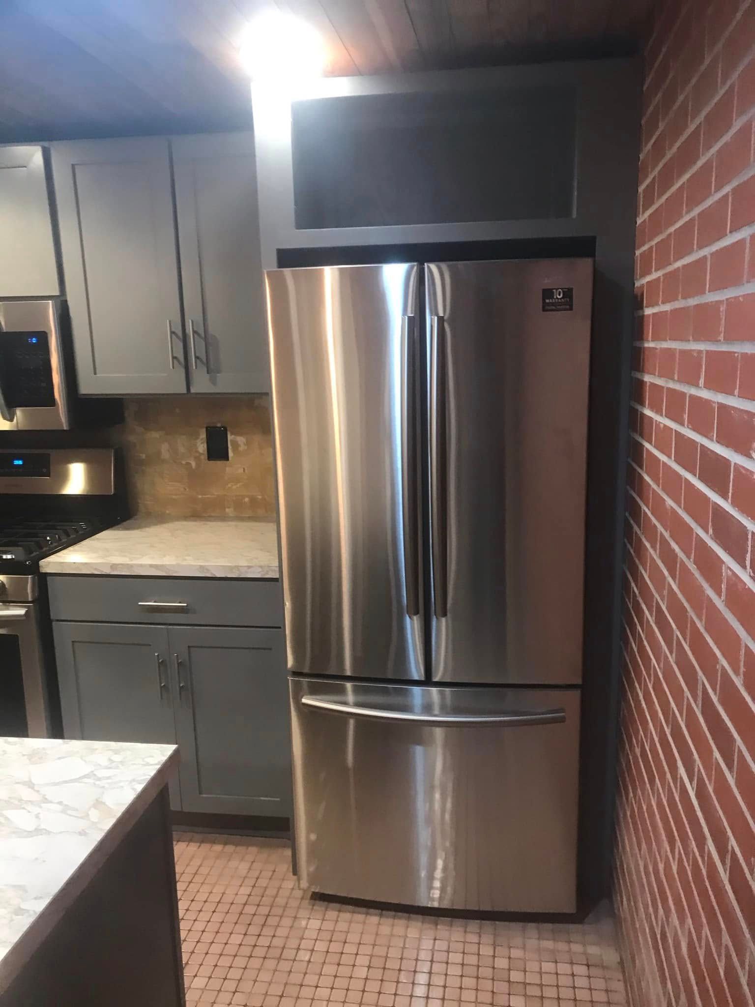 Kitchen counter with double sink, wooden countertop, dark cabinets, and exposed brick walls Kitchen counter with double sink, wooden countertop, dark cabinets, and exposed brick walls