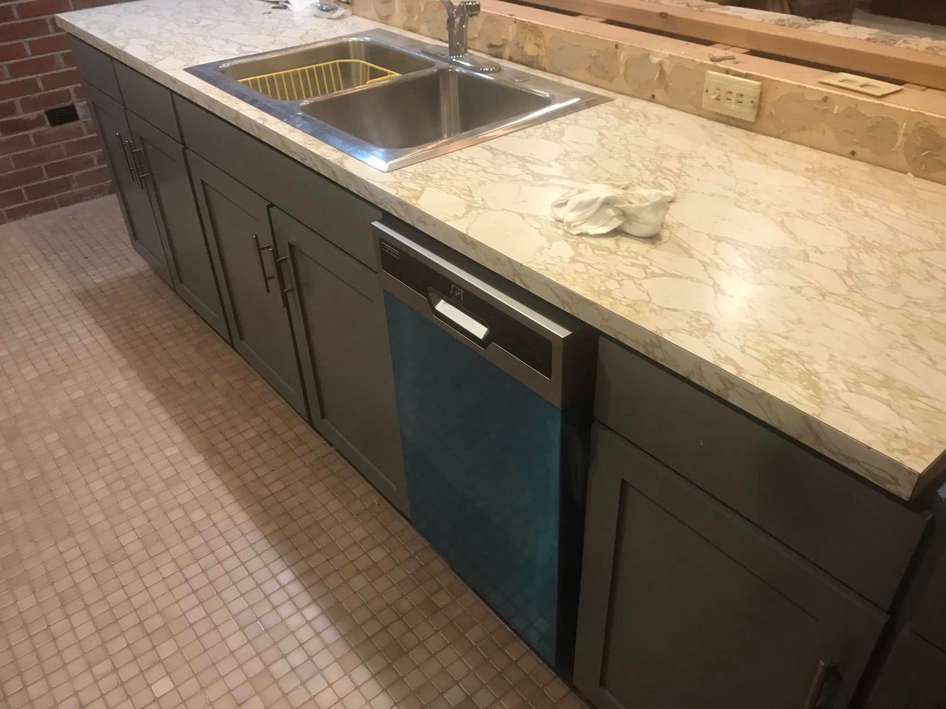Modern kitchen island with stainless sink, beige stone countertop, and dark cabinets Modern kitchen island with stainless sink, beige stone countertop, and dark cabinets