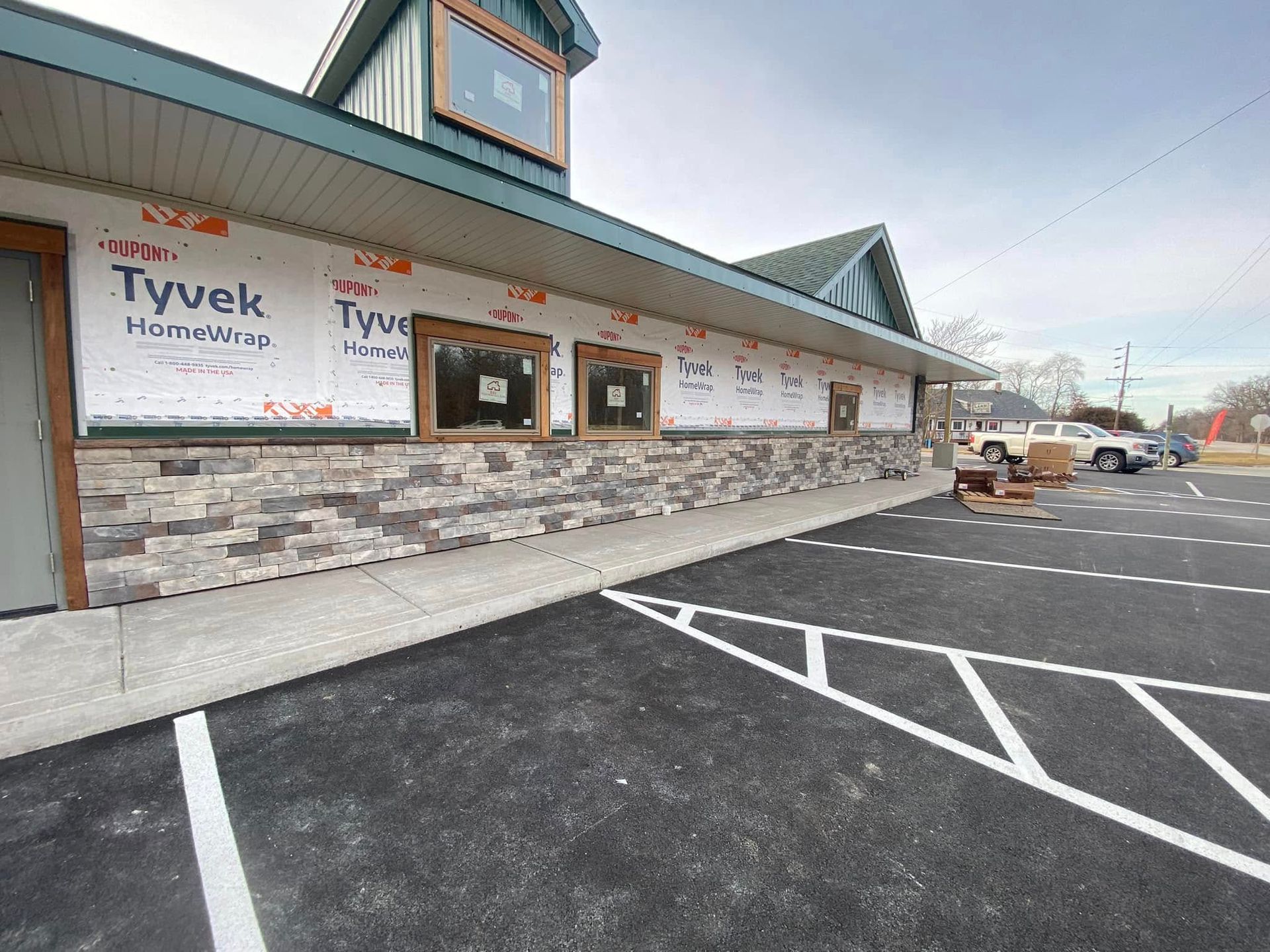 Drive-thru restaurant exterior with stone siding, menu boards, and empty parking spaces on a sunny day