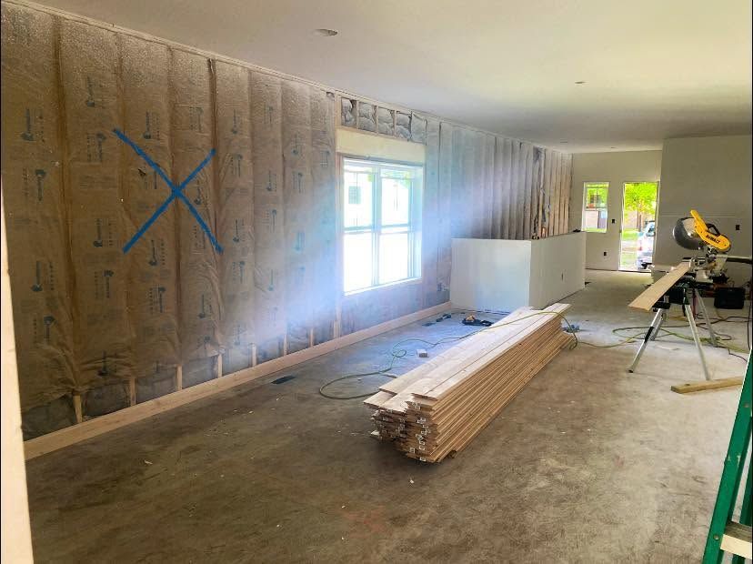 Renovation room with stacked lumber, window light, and a miter saw on a stand Renovation room with stacked lumber, window light, and a miter saw on a stand