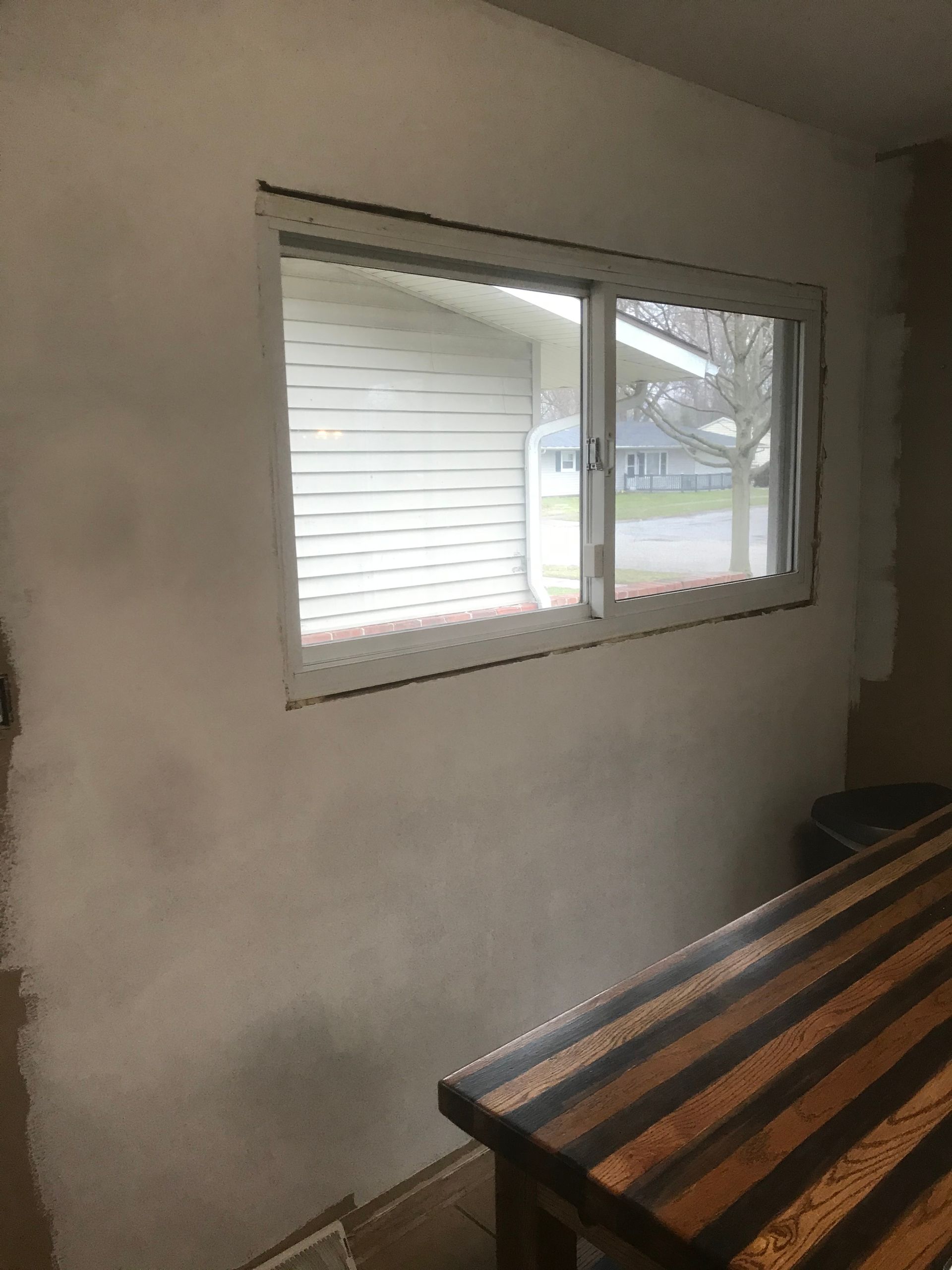 Empty room with a window, beige walls, and a striped table in the foreground