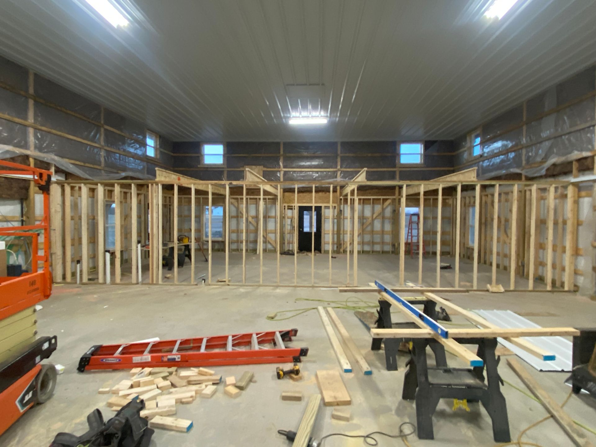 Back patio under construction with wooden posts, covered grill, and grassy yard beside a house Back patio under construction with wooden posts, covered grill, and grassy yard beside a house