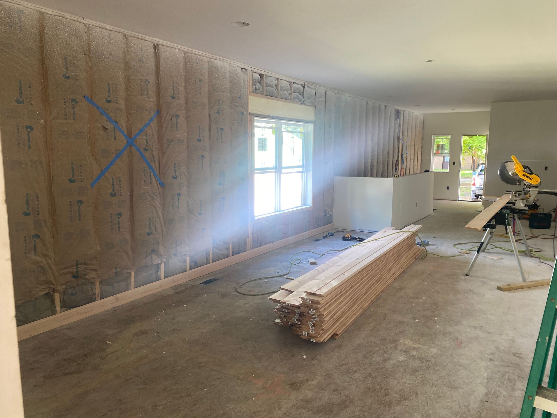 Renovation room with stacked lumber, tools, and a partially finished wall and window.
