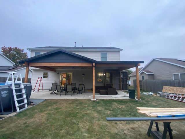 Backyard patio with covered porch, outdoor furniture, and a ladder beside the house