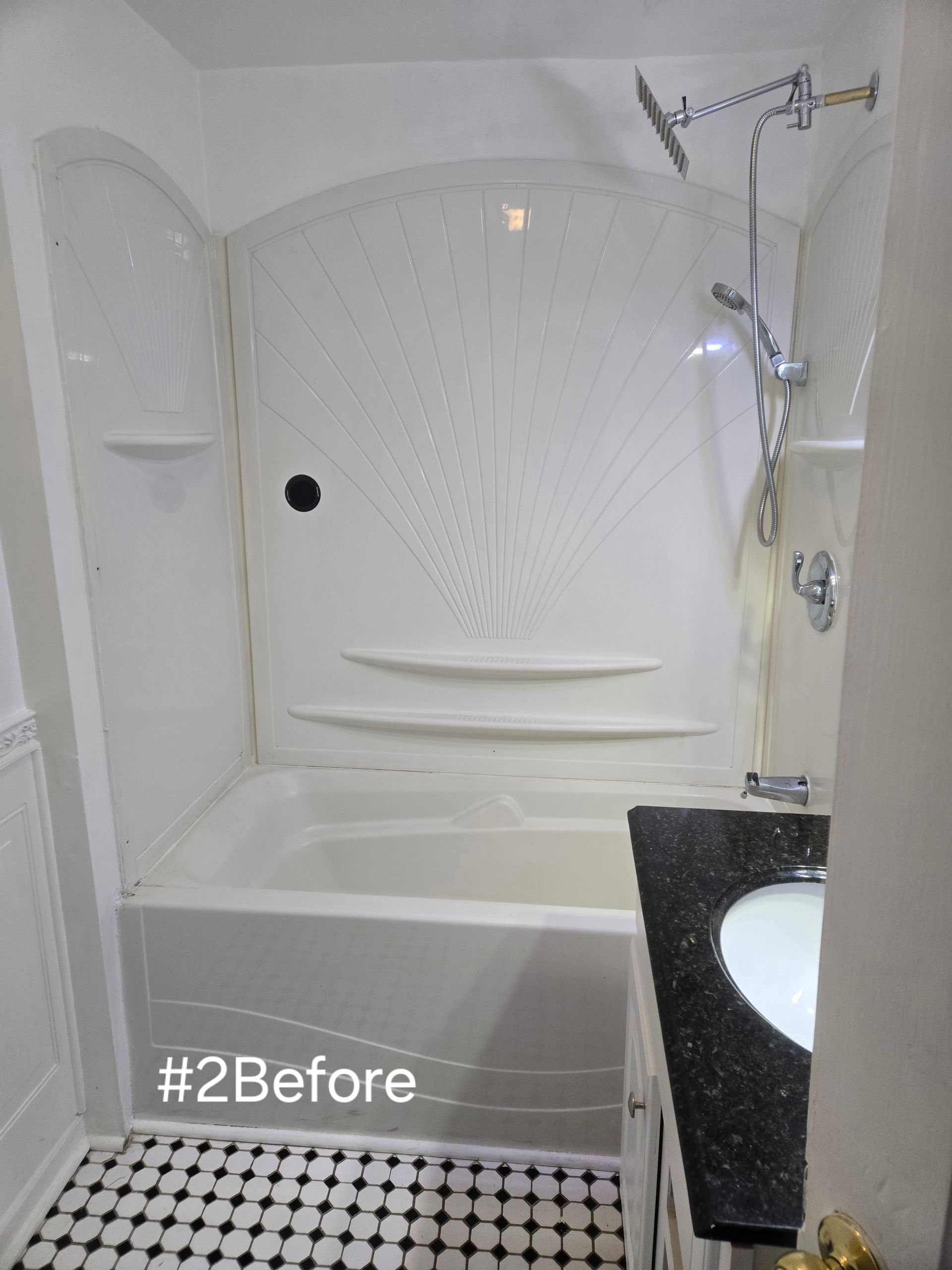 White bathtub shower with black countertop vanity and black and white tiled floor.