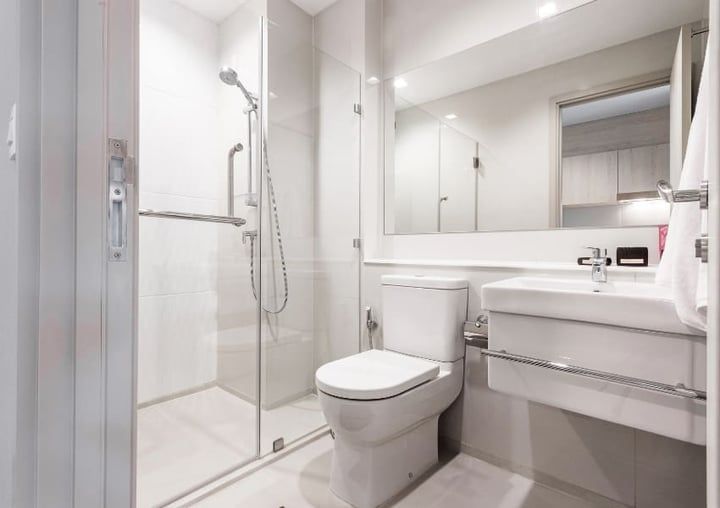 Bright white modern bathroom with glass shower, toilet, and vanity.