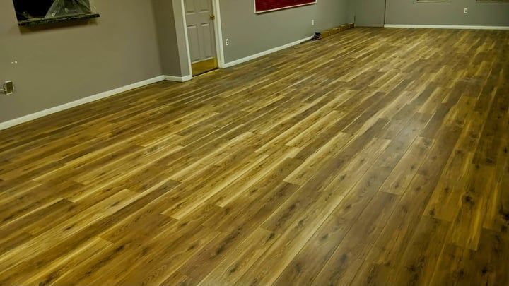 Newly installed hardwood floors in a room with gray walls and a doorway.