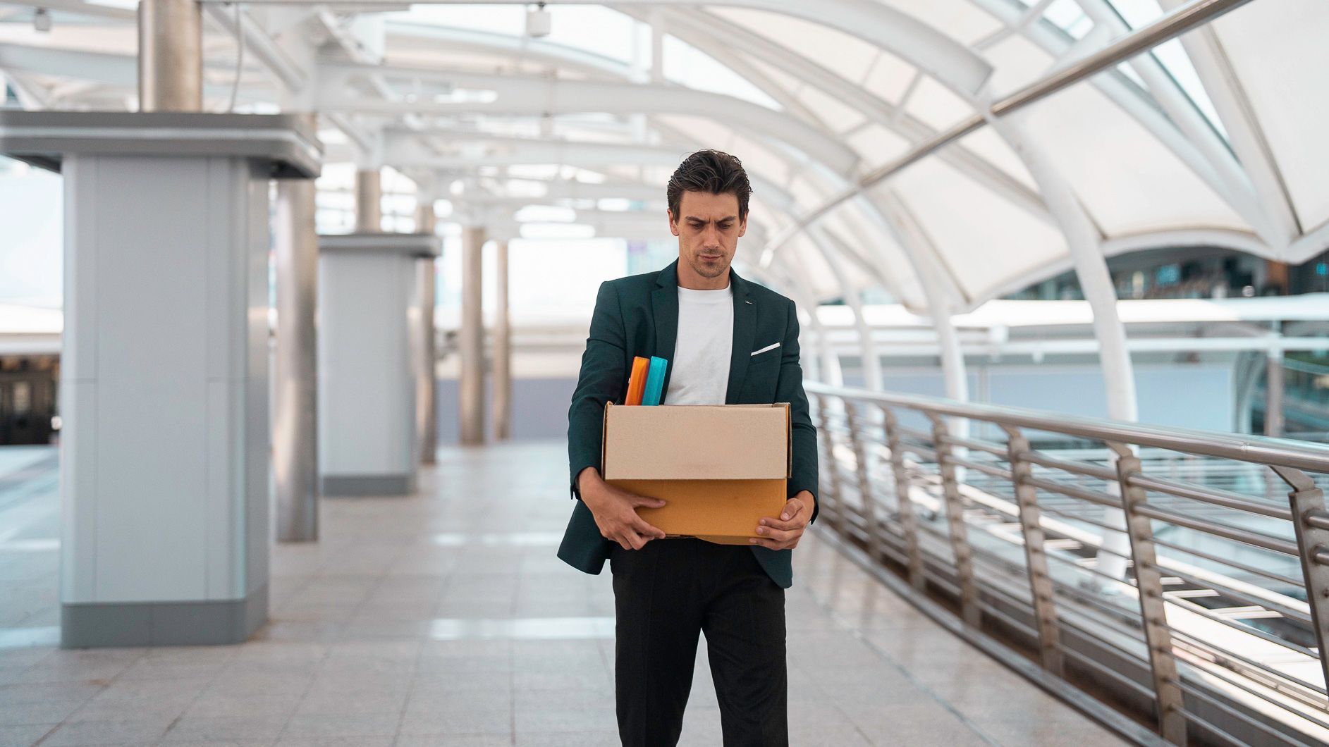 Man carrying a box through a bright airport walkway