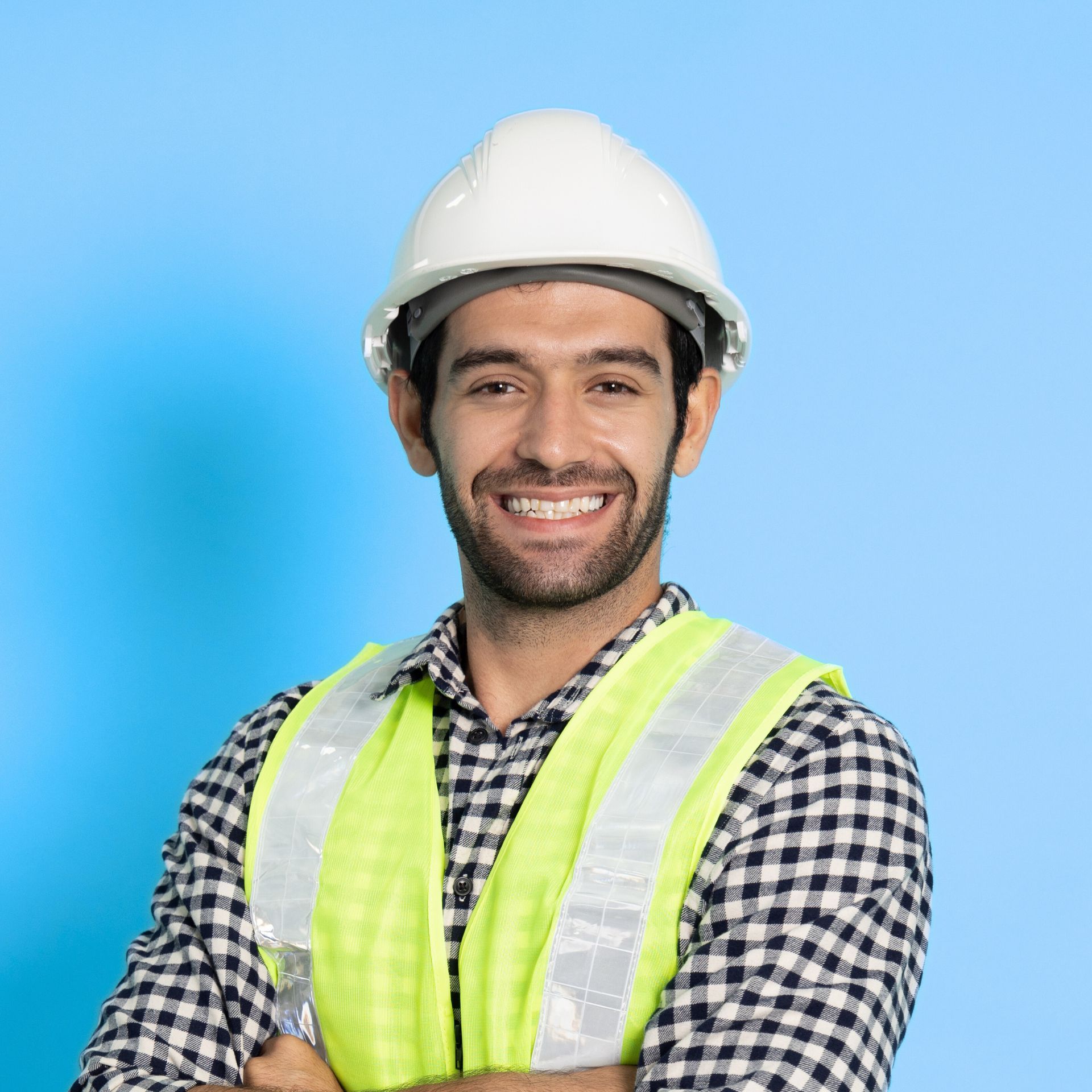 Construction worker wearing a white hard hat and reflective vest, smiling with arms crossed, blue background.