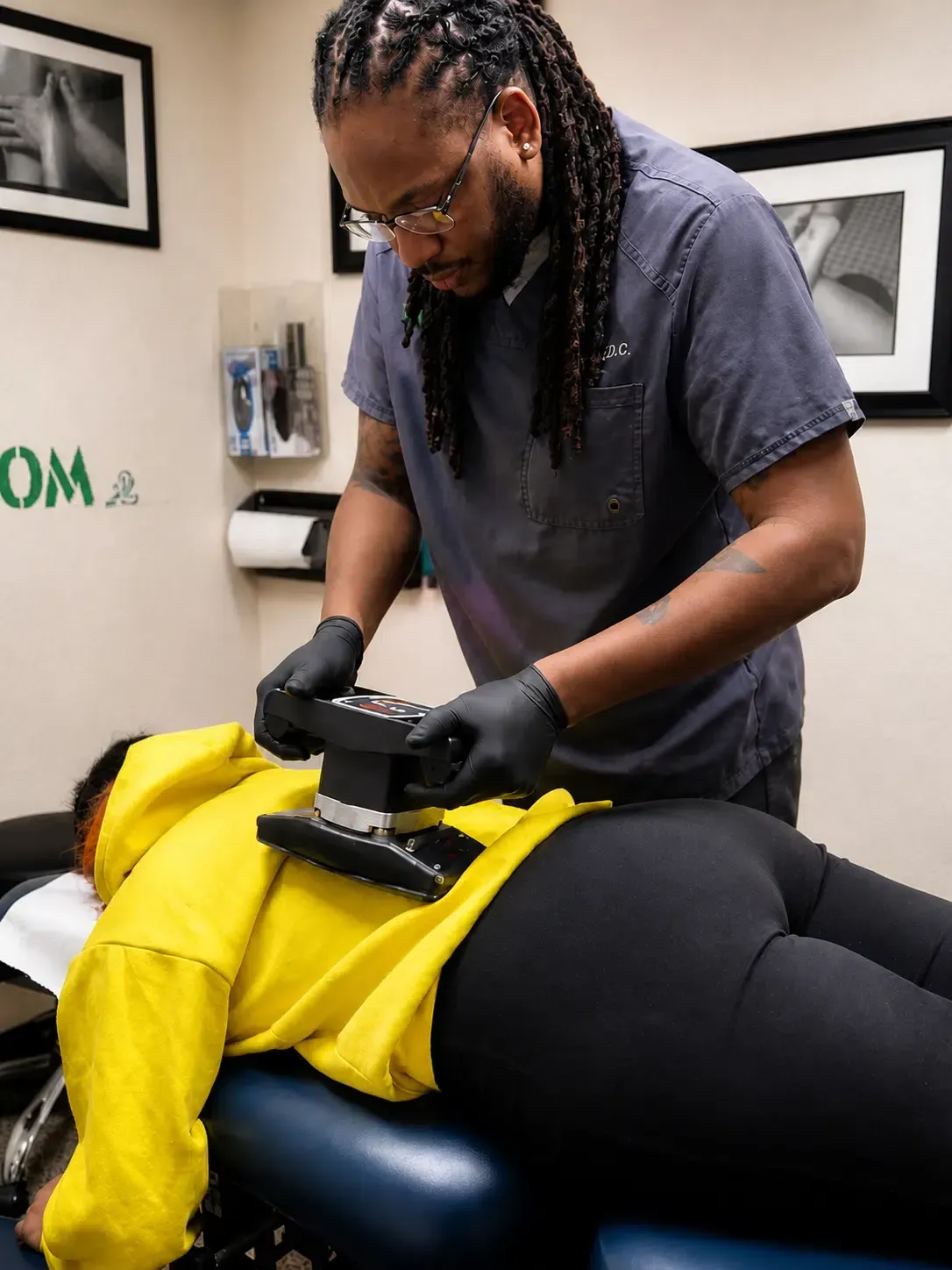 Person receiving a back massage on a treatment table while the therapist works with a handheld device