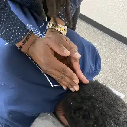 Hands resting gently on a person’s head in a close-up, likely in a comforting or prayer gesture.