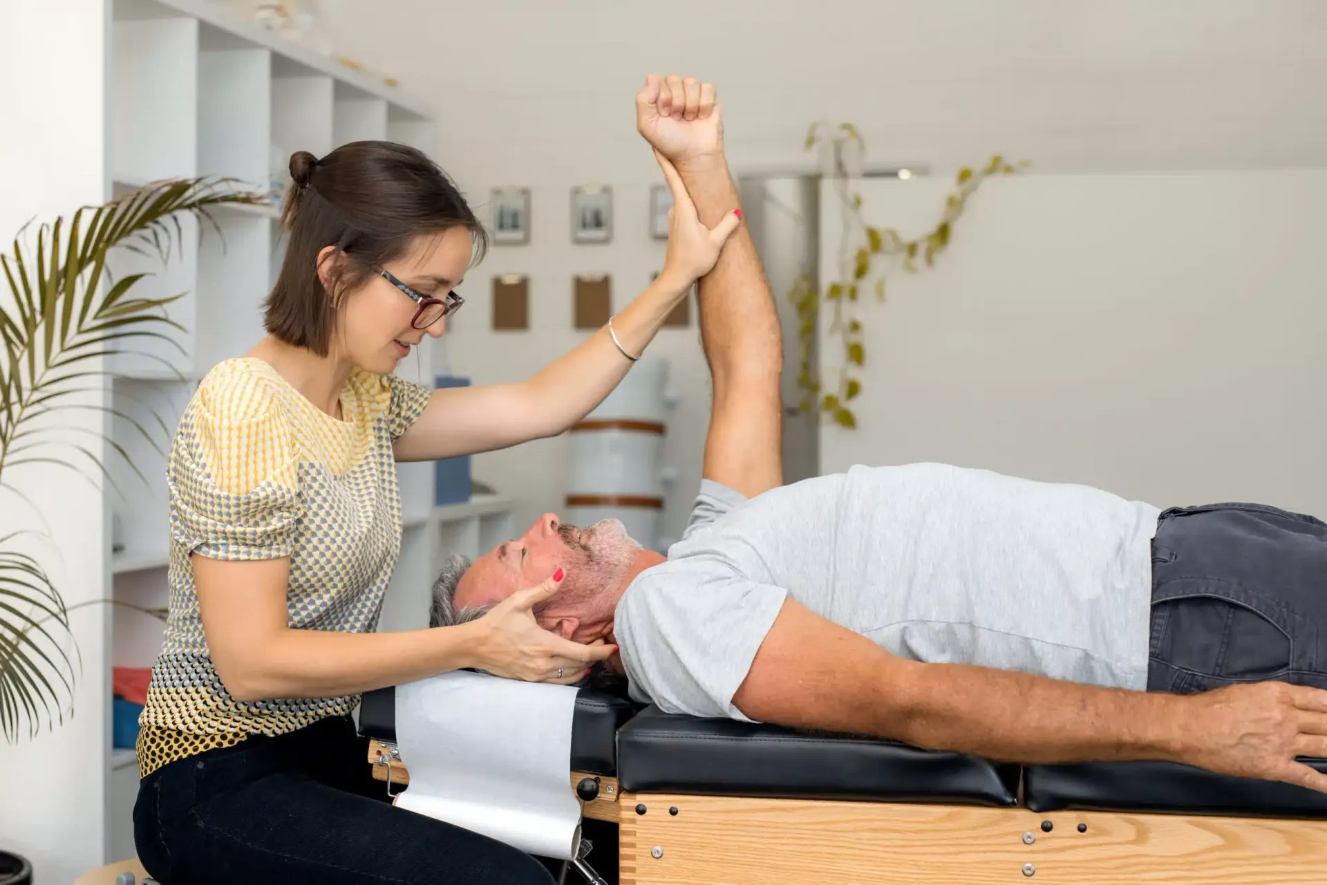 Physical therapist stretching a patient’s arm on a treatment table in a clinic room.