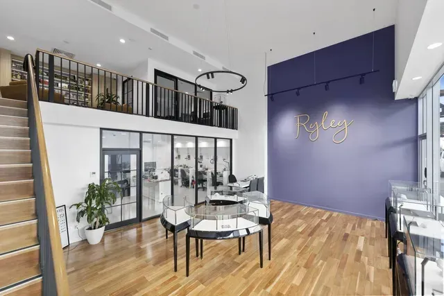 Modern office lobby with high ceilings, wood floors, glass partitions, and a purple accent wall