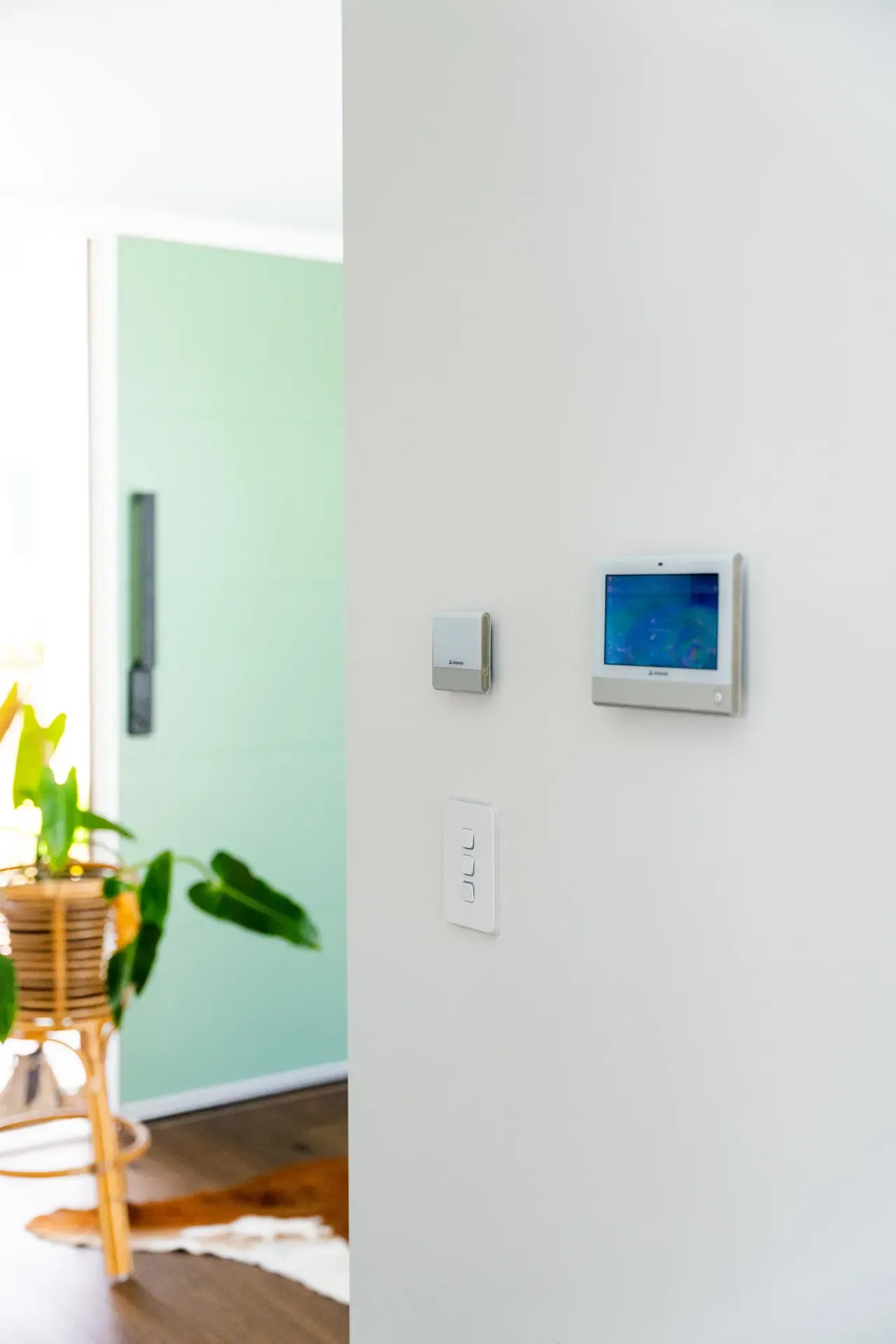 Wall-mounted thermostat and switch panel on a white wall beside a frosted glass door.