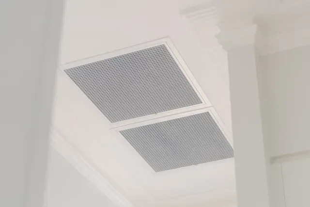Two rectangular ceiling vents with white frames on a white interior ceiling