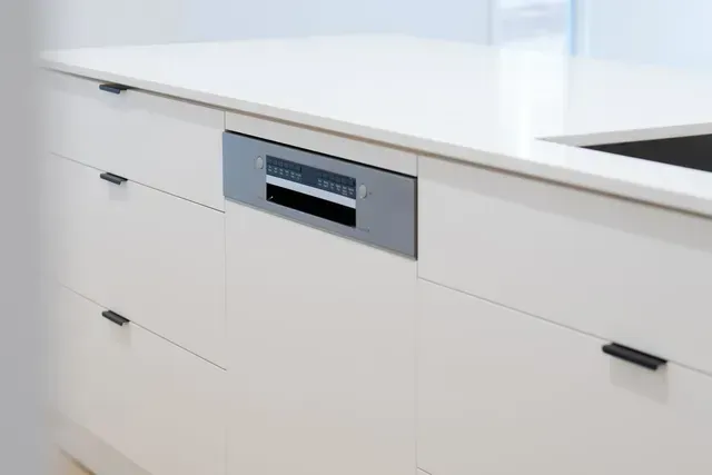 White kitchen island with drawers and a built-in stainless steel oven front