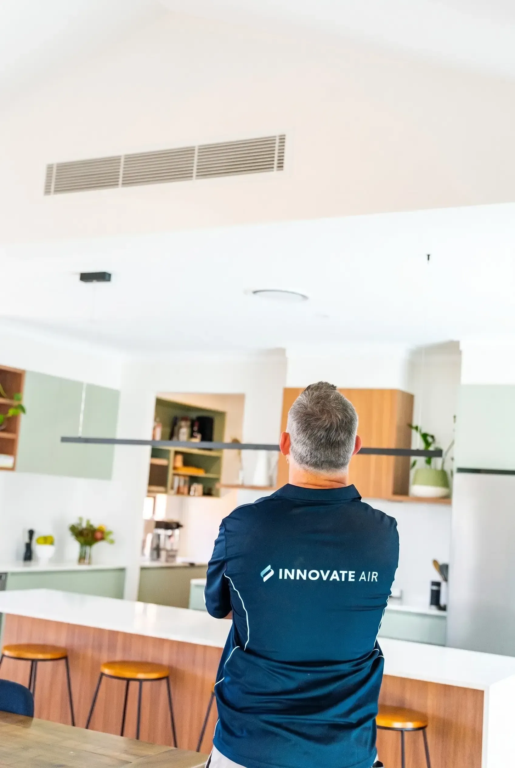Person in navy shirt standing at a white kitchen counter in a bright, modern home interior