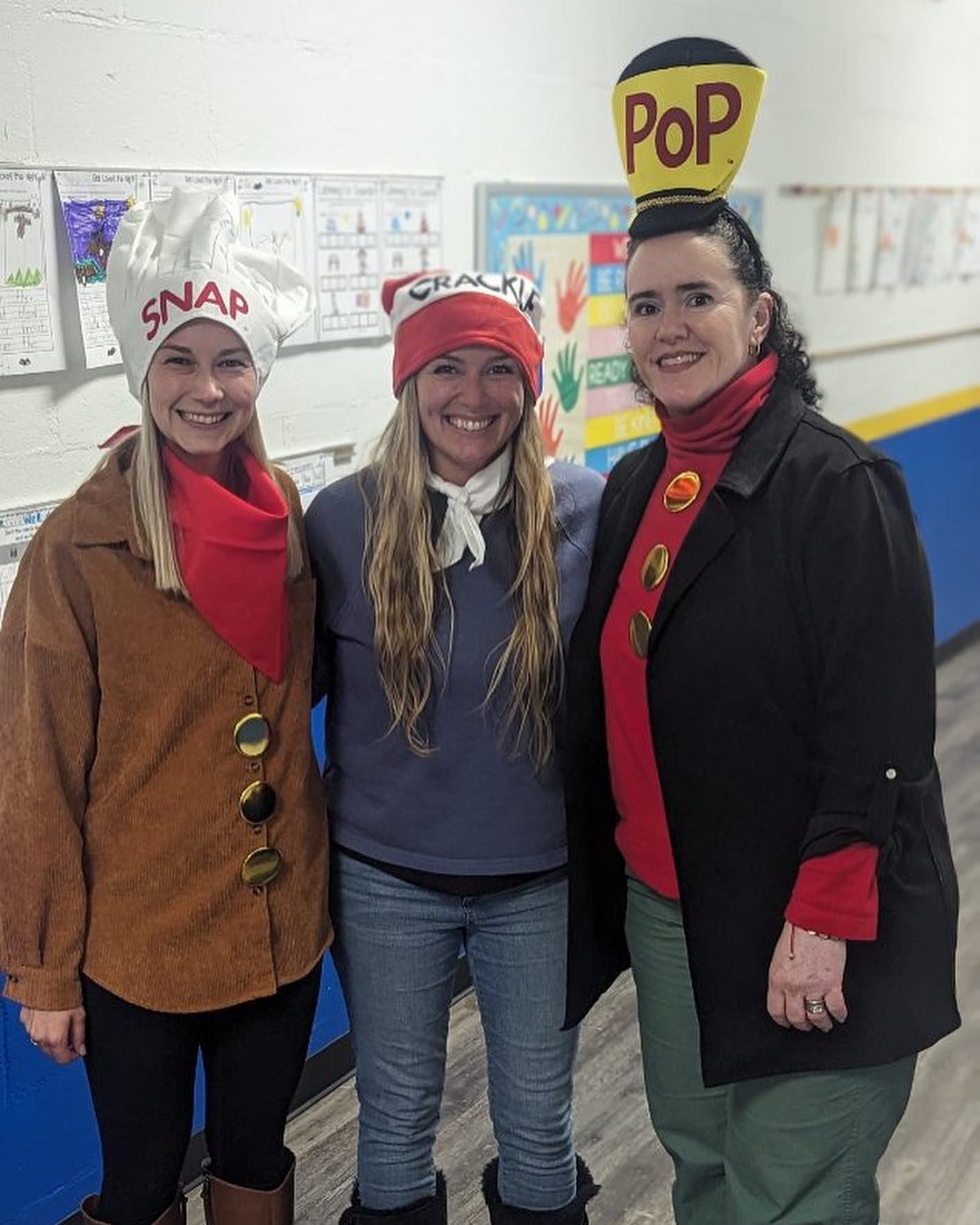 three women are posing for a picture in a hallway .