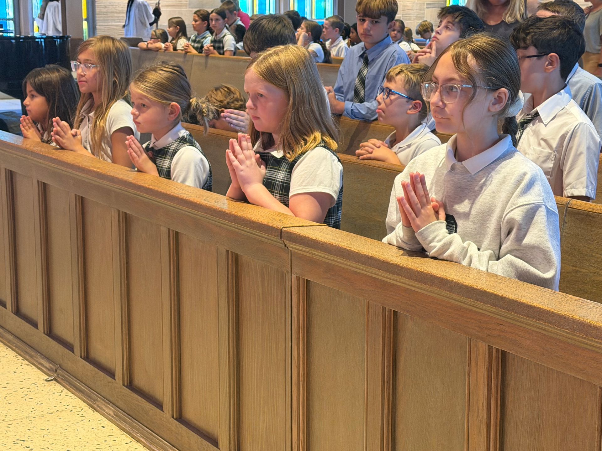 a group of people are standing in a church holding candles .