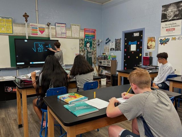 two young boys are sitting at a desk in a classroom .