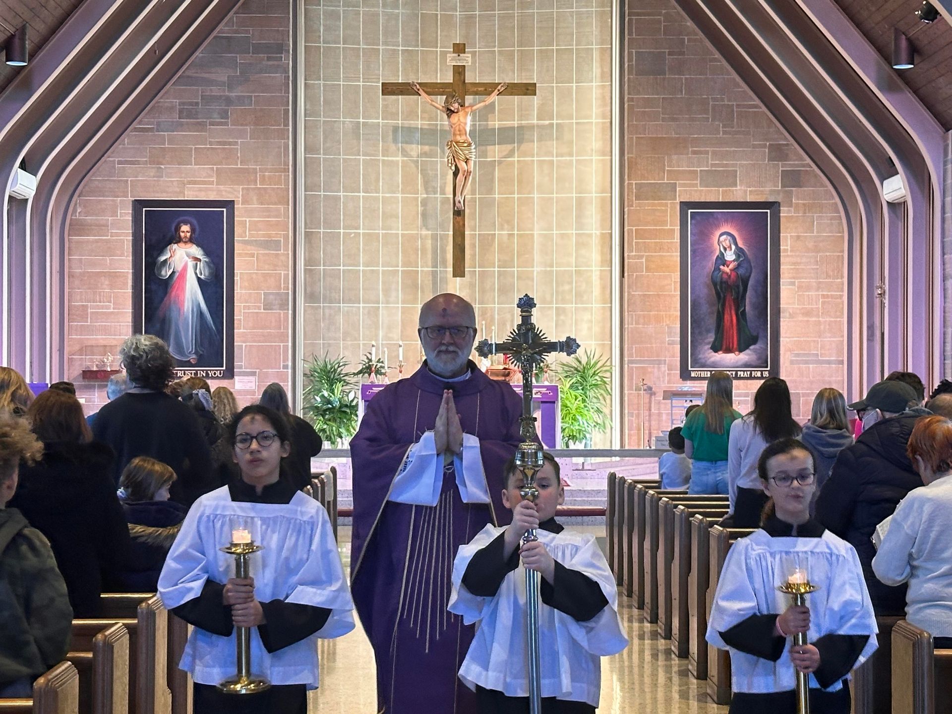 a group of people are standing in a church holding candles .