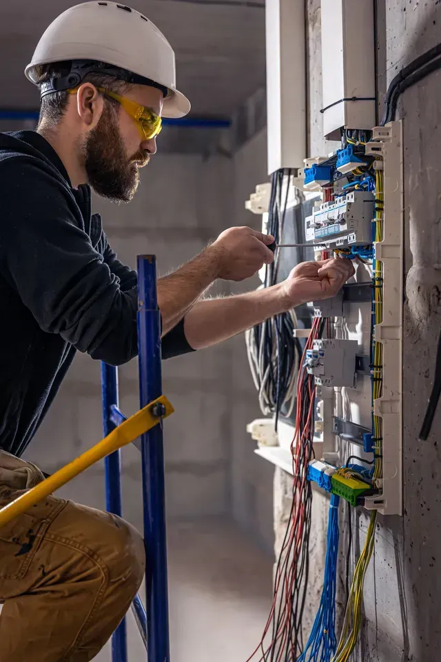 Un électricien travaille sur un coffret électrique dans un immeuble.