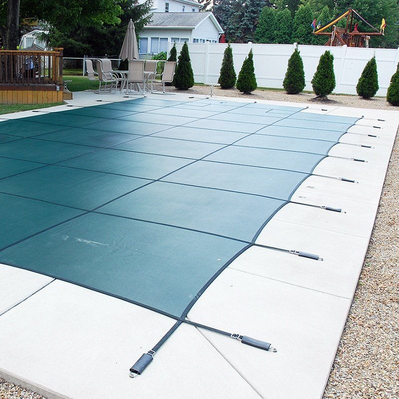 A partially open swimming pool cover rolled back, showing blue water inside a concrete pool area