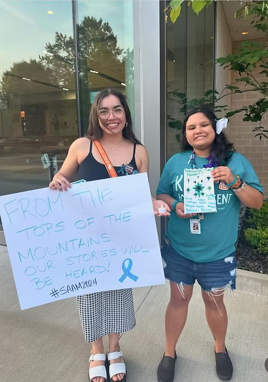 Two people hold signs: