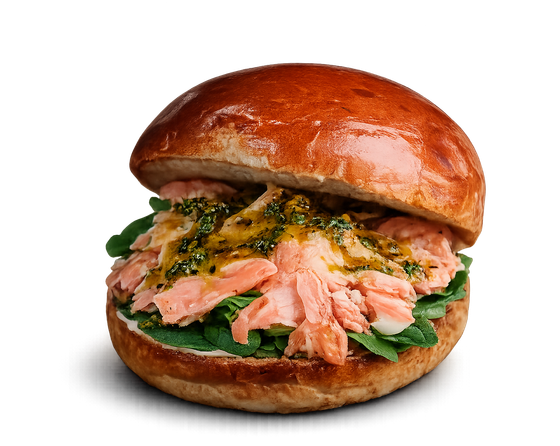 Primo piano di un panino brioche lucido con salmone, verdure e salsa su sfondo bianco.