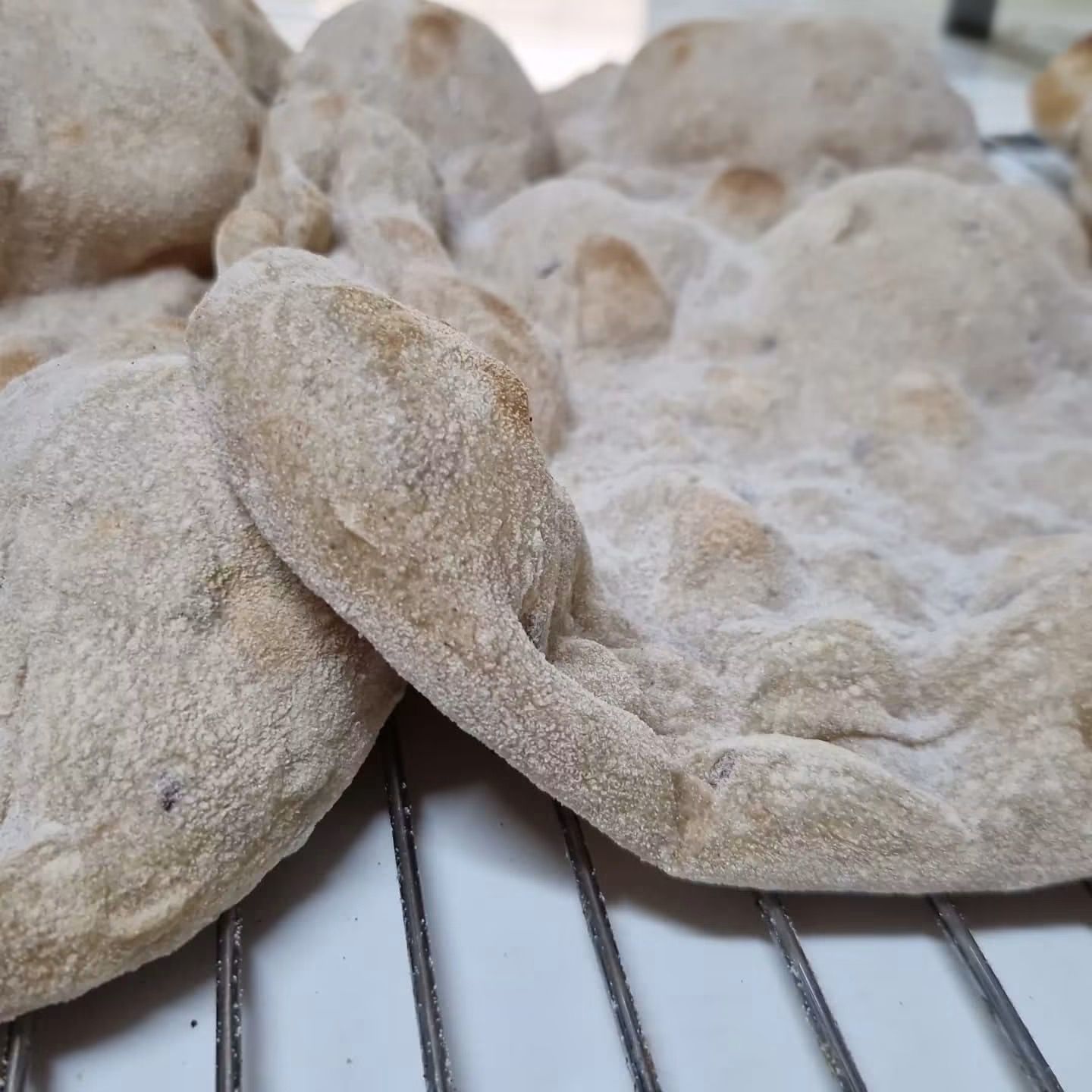 Pezzi di pasta infarinata disposti su una griglia, pronti per essere infornati.