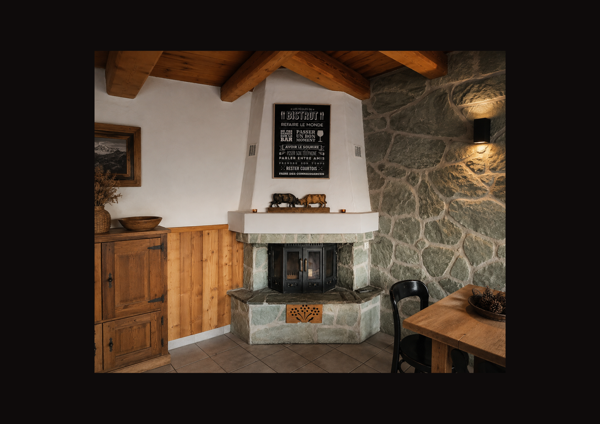 Coin cheminée rustique et chaleureux avec mur en pierre, poutres en bois, armoire et petite table à manger