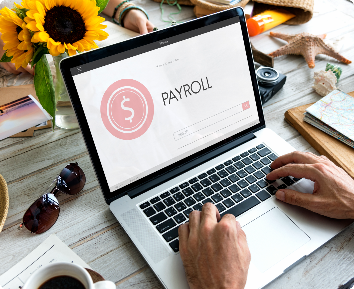 A person is typing on a laptop computer with the word payroll on the screen.