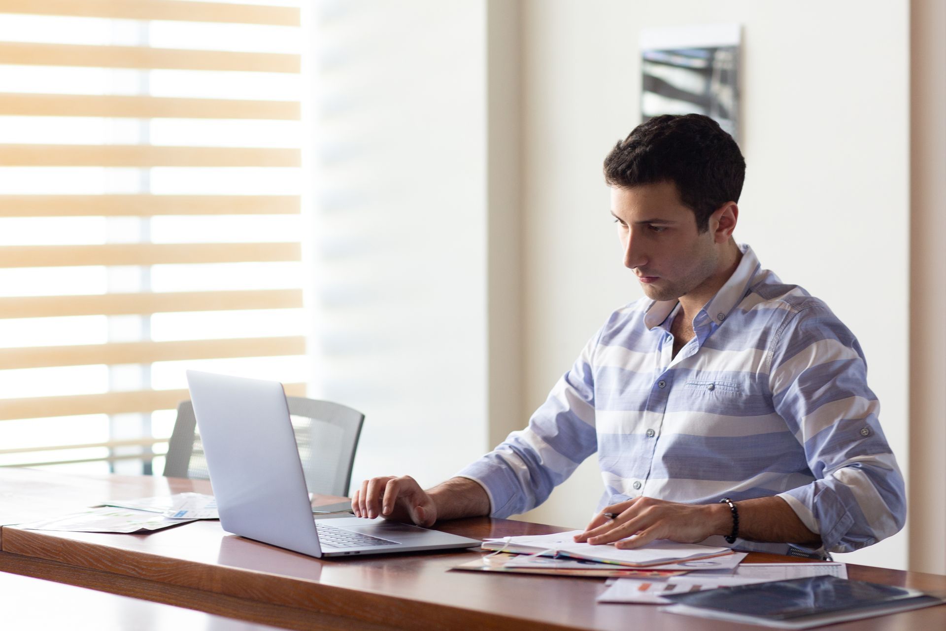 Couple reviewing documents with a professional at a table, smiling. Laptop visible.