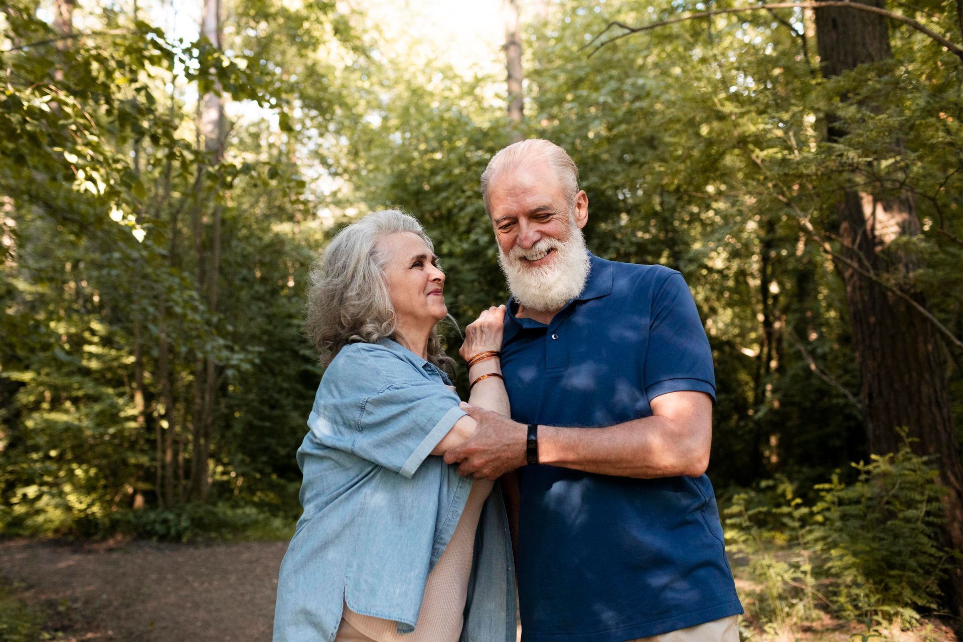 Family of three on a sofa, laughing; father reading tablet, mother stroking child's hair, lamp in background.