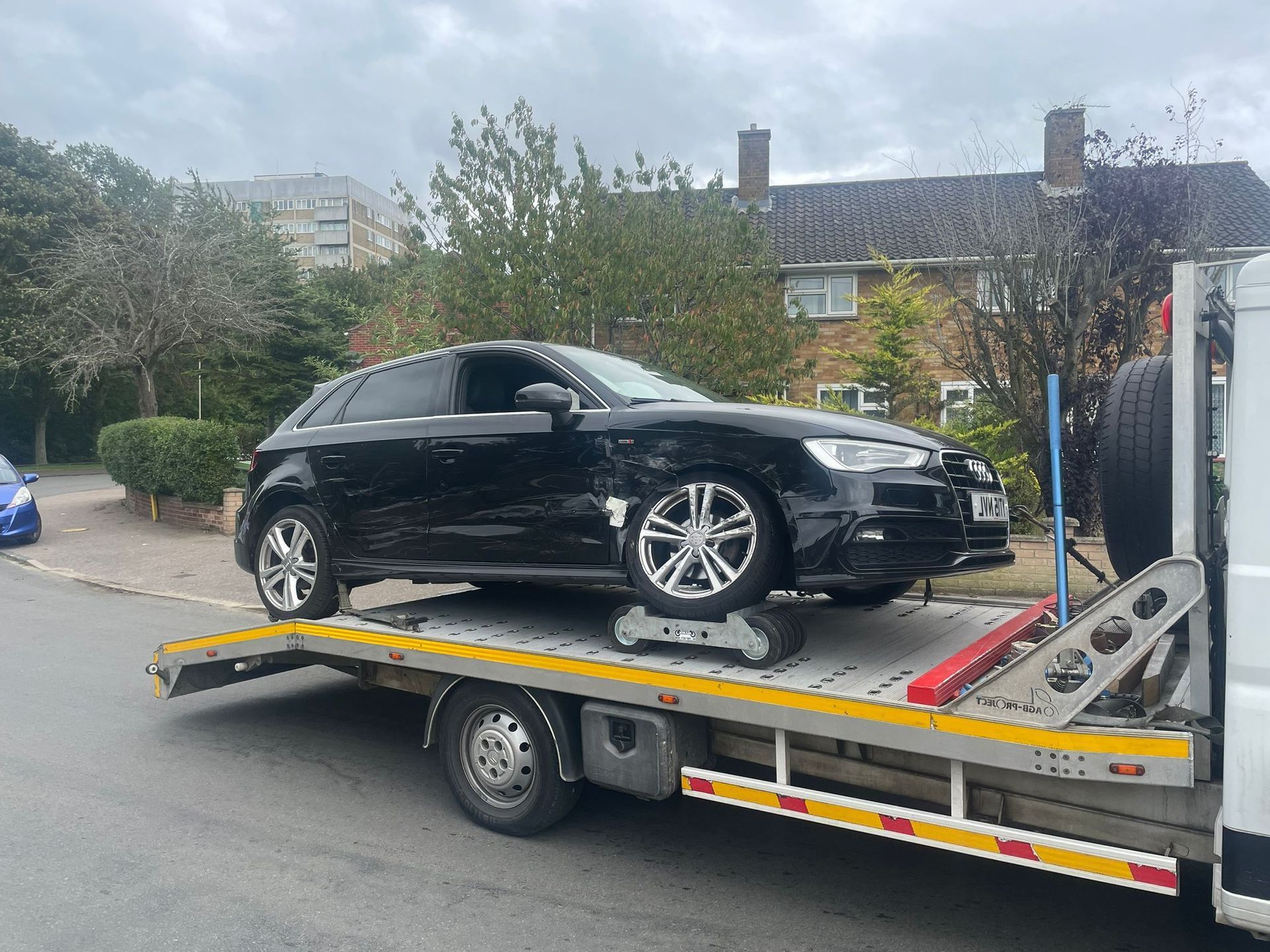 A black car is sitting on top of a tow truck.