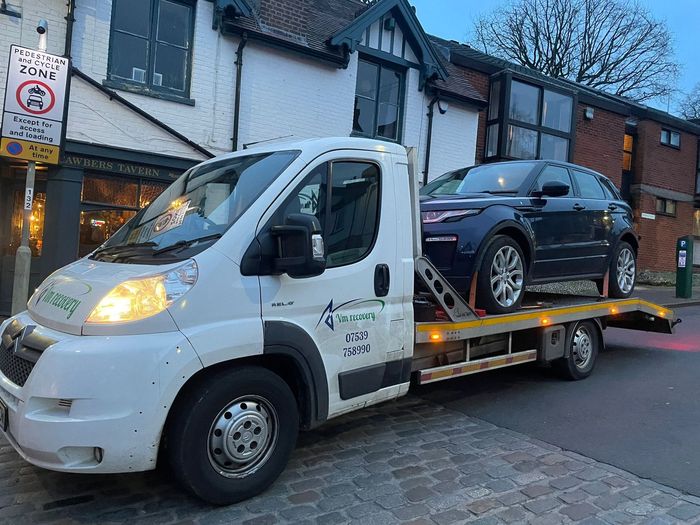 A tow truck is carrying a car on the back of it.