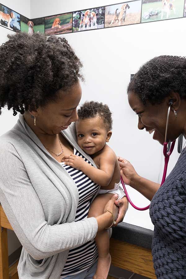 Doctor examining a child while parent holds them in a clinic setting