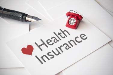 Health insurance card with red heart and red phone beside a pen