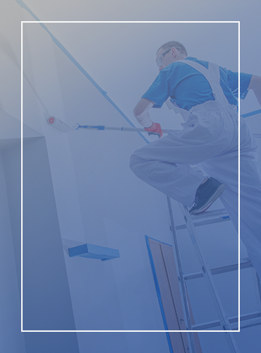 a man is sitting on a ladder painting a wall with a roller .