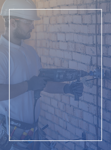 a man is using a drill to drill a hole in a brick wall .