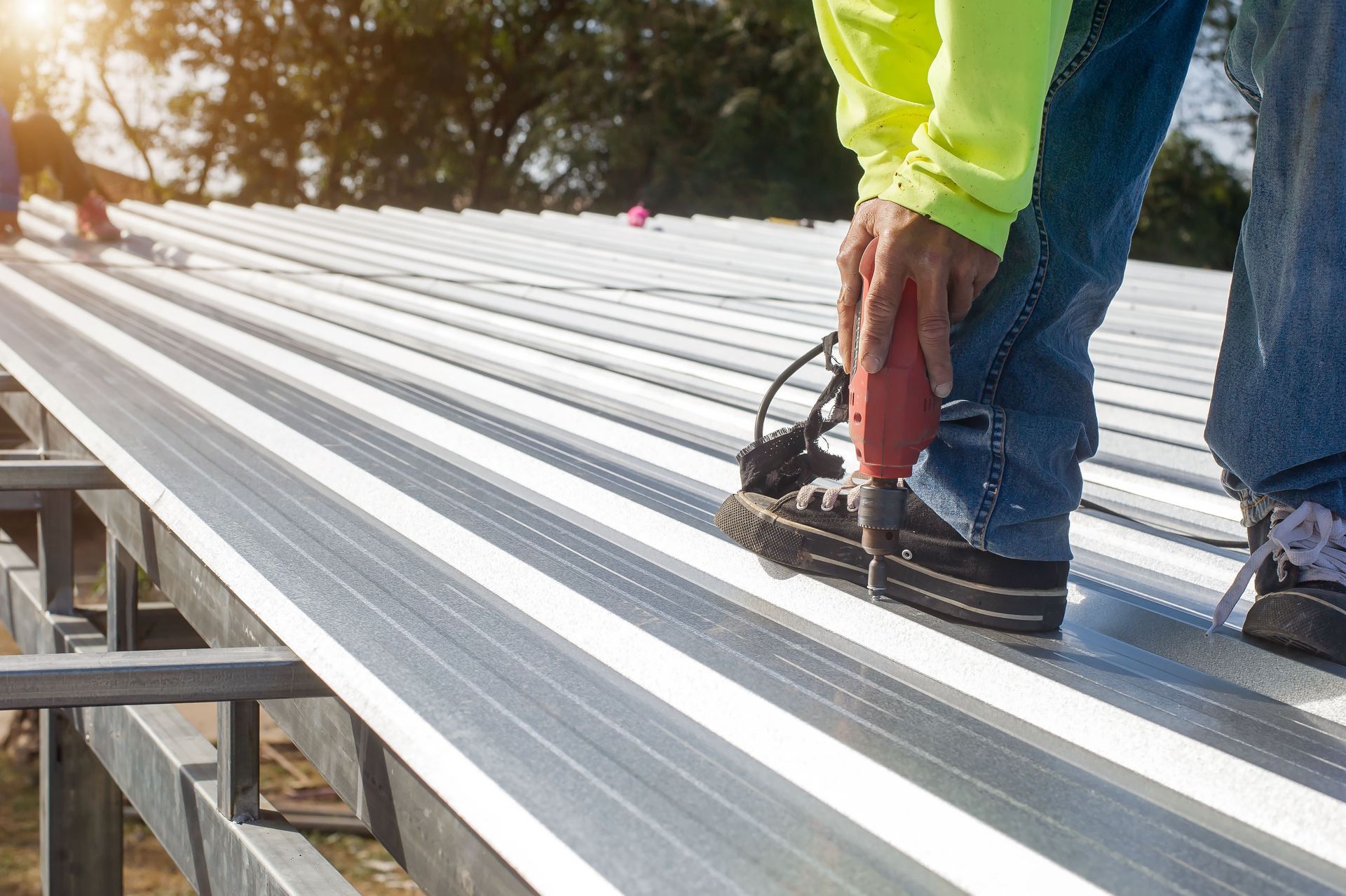 a man is working on a metal roof with a drill .