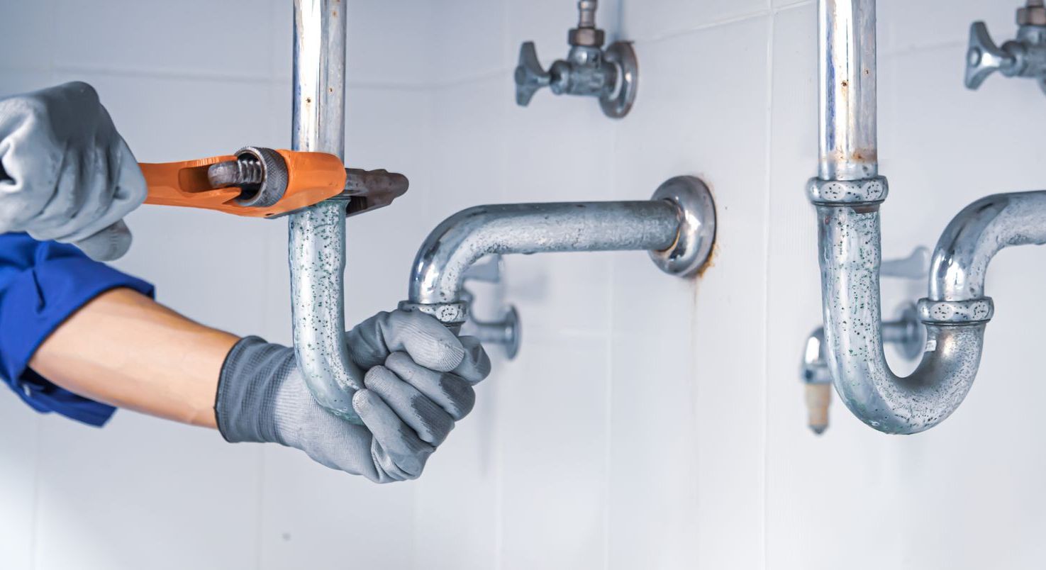 a plumber is fixing a sink pipe with a wrench .