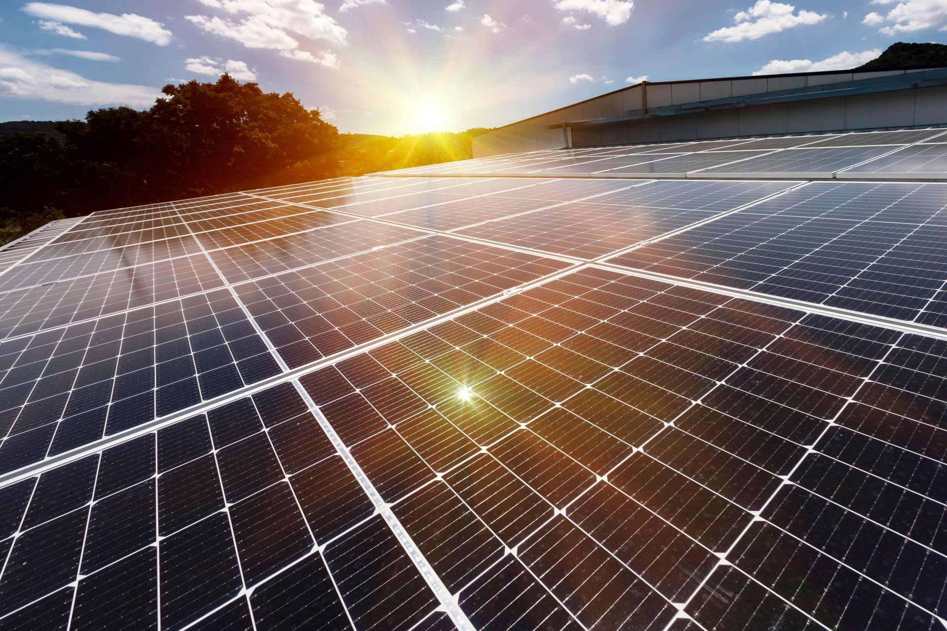 a row of solar panels on a roof with the sun shining through them .