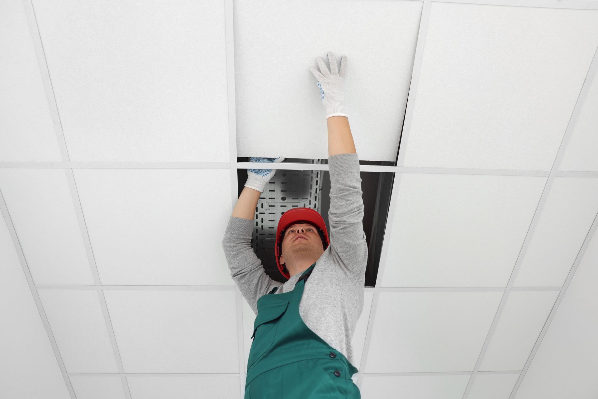a man is hanging a light fixture from the ceiling .